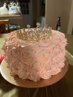 a pink cake with roses and a tiara on top