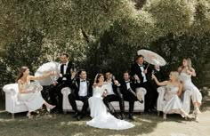 a group of people sitting on top of white couches in front of some trees