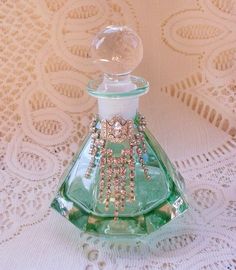 a green glass bottle sitting on top of a lace covered tablecloth with a white doily behind it