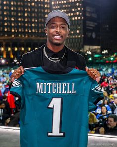 a man holding up a football jersey in front of a crowd