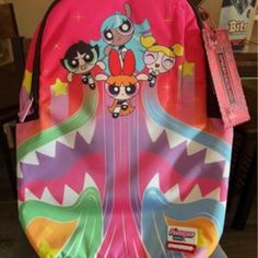 About Features Version 2 Backpack From Sprayground X The Powerpuff Girls. Official Sprayground And The Powerpuff Girls Collaboration. Sublimated Graphics Throughout. Roomy Main Compartment With Two Zippered Pockets. External Pocket With Vertical Zip Closure On The Front. Velour Lined Laptop And Sunglasses Compartments. Dual Water Bottle Sleeves With Hook-And-Loop Closures. Adjustable Padded Shoulder Straps. Ergonomic Mesh Back Padding. Slide-Through Design For Luggage Travel. Custom Brand Hardwa Sprayground Backpack Powerpuff, Sprygraund Backpack, Sprayground Backpack Outfit, Sprayground Backpack Pink, Sprayground Bookbags, Spray Ground Backpack, Short Green Hair, Girly Backpacks, Sprayground Backpack