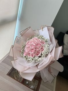 a bouquet of pink roses and baby's breath wrapped in paper