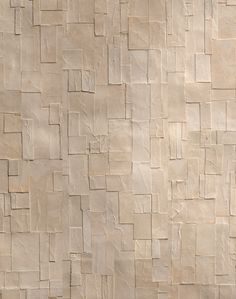 an abstract wall made up of squares and rectangles in neutral tones, with a bench on the side