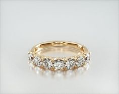 a yellow gold wedding ring with five diamonds on it's side and the center stone is