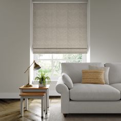 a white couch sitting next to a window in a living room under a roller shade