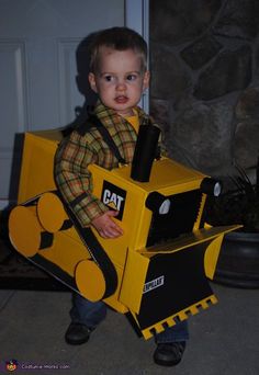 a young boy dressed up as a construction worker holding a cardboard box with a cat on it