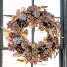 a wreath hanging on the side of a window sill with leaves and acorns