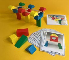 several different colored wooden toys and cards on a yellow surface