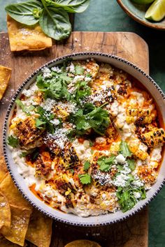 a bowl of mexican food with tortilla chips and cilantro on the side