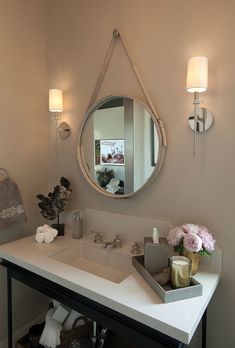 a bathroom sink with a mirror above it and flowers on the counter top next to it