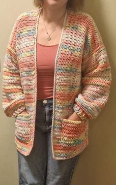 a woman standing in front of a wall with her hands on her hips and wearing a crocheted cardigan