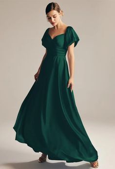 a woman in a long green dress is looking down at the camera and she has her hand on her hip