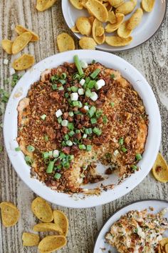 a white plate topped with food next to two plates filled with potato chips and green onions