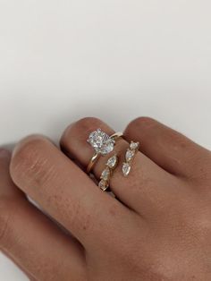 a person's hand with two rings on their fingers and one has an engagement ring in the middle