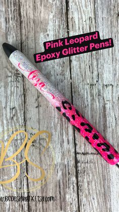 the pink leopard epoxy glitter pen is laying on top of a wooden table