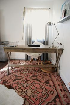 a room with a rug, desk and lamp