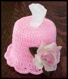 a crocheted pink hat with a flower on the top and tissue paper in the middle