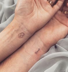 two people with matching tattoos on their wrists holding each other's hands together