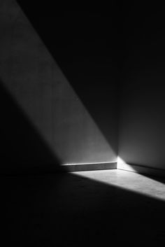 a black and white photo of an empty room with light coming in from the window