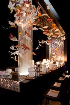 an artistic display in the dark with candles and paper birds flying around on top of it