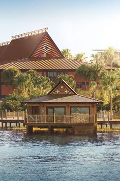 a house sitting on top of a body of water next to a dock and palm trees