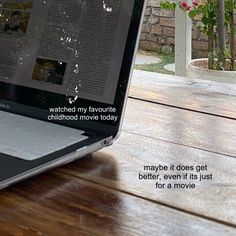 an open laptop computer sitting on top of a wooden table next to a brick wall