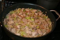 a skillet filled with meat and vegetables cooking on the stove