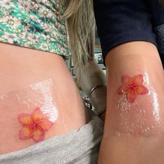 two women with flower tattoos on their stomachs