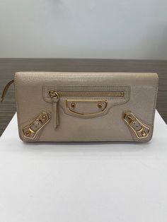 This is an authentic pre-owned BALENCIAGA Classis Metallic Edge Long Wallet. DESCRIPTION: This leather wallet features gold-tone hardware, buckle and stud detail, and an exterior front zip pocket. It has a hidden snap closure. The inside has 8 card slots, 4 bill slots, and one zip pocket.  CONDITION: The exterior shows some visible rubs and wears on the corners and some fading on the gold-tone hardware. The interior is clean with some minor rubs on the leather. MEASUREMENTS: Approx. 4"H x 7.5"W Amazing Watches, Envelope Wallet, Louis Vuitton Damier Ebene, Money Clip Wallet, Metallic Logo, Long Wallet, Authentic Louis Vuitton, Vintage Gucci, 4 H