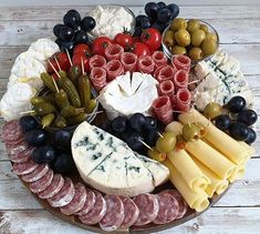 a platter filled with cheese, meats, olives, and other foods