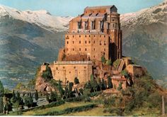 an old castle on top of a mountain with snow capped mountains in the back ground