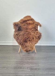 a chair made out of fur with wooden legs on the floor in front of a white wall