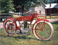 an old red motorcycle is parked in the grass