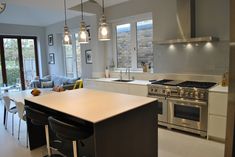 a modern kitchen with stainless steel appliances and white counter tops, along with seating for four