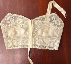 This camisole is from the time that the camisole was becoming a bra.  It has a label of 2 words.  I'm not sure of the first word, it resembled Scott's; the second word is Ideal.  It shows Chicago.  I've not found any mention of this name. This sweet garment is made of silk and filet lace.  The silk cups have some deteriorated holes.  One strap is missing and the other is frayed.  These could easily be replaced.  The label is attached at the bottom of the camisole.  The closure is hook and eyes. Fitted Vintage Camisole, Vintage Sleeveless Top With Built-in Bra, Vintage Sleeveless Camisole With Built-in Bra, Vintage Fitted Camisole With Built-in Bra, White Vintage Camisole For Daily Wear, Vintage Sleeveless Wedding Tops, Vintage White Camisole For Daywear, Vintage Cami Top For Daywear, Vintage Camisole Top For Daywear