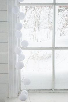 a cat sitting in front of a window with white pom - poms on it's tail