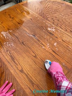 a person in pink gloves painting a wooden table