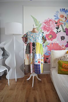 a dress on a mannequin in front of a colorful wallpapered room