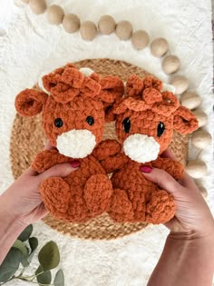 someone holding up a small stuffed animal on top of a white rug next to a plant