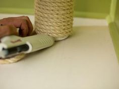 a person using a hair dryer on top of a white counter next to a rope