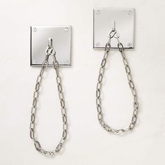 a pair of metal chains hanging from a hook on a white wall next to a mirror