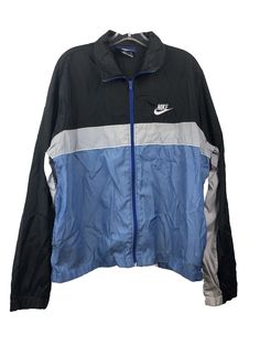 Elevate your vintage clothing collection with this Nike Blue Tag Windbreaker Jacket in a striking black and blue colorblock pattern. This lightweight jacket features a full zip and pockets, making it both stylish and functional. Perfect for men who love 80s fashion, this windbreaker is made with nylon outer shell material and has a zipper closure. With a chest size of 45 inches and size L, this jacket is a great addition to any wardrobe. The Nike brand ensures quality and the vintage design adds a touch of nostalgia. Don't miss out on the opportunity to own this statement piece. Hole on lower front. Some fading. Men’s Large Chest - 22.5” Length - 27” Nike Blue Sports Windbreaker, Blue Nike Windbreaker With Pockets, Navy Vintage Windbreaker For Streetwear, Retro Blue Nylon Windbreaker, Blue Nylon Windbreaker With Double-lined Hood, Nike Vintage, Nike Brand, Nike Blue, Chest Size