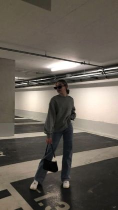 a woman is standing in an empty parking garage