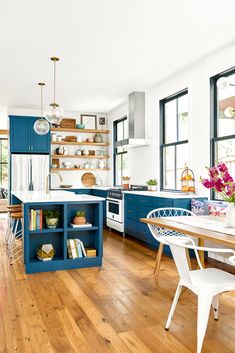 a kitchen with wooden floors and blue cabinets, white counter tops, and open shelving