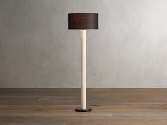 a lamp that is sitting on top of a wooden floor in front of a wall