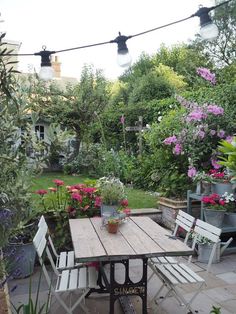 a wooden table sitting in the middle of a garden next to some potted plants