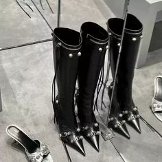 The Clara Buckle Detail Knee-High Boots are designed to make a bold fashion statement. Crafted in sleek black leather, these pointed-toe boots feature a modern, edgy look with buckle accents and a side zipper for easy wear. The stiletto heel adds height and sophistication, making these boots perfect for nights out or elevating your everyday style. The knee-high length elongates the legs, while the subtle buckle detailing adds a touch of character to this classic piece. Details: Black high qualit Formal Gothic Boots With Pointed Toe, Chic Pointed Toe Moto Boots For Formal Wear, Designer Knee-high Boots With Pointed Toe For Party, Edgy Moto Boots With Metal Feet For Parties, Chic Moto Boots With Pointed Toe For Formal Occasions, Gothic Heeled Boots With Pointed Toe For Fall, Chic Formal Moto Boots With Pointed Toe, Edgy Knee-high Moto Boots For Party, Punk Style Leather Knee-high Boots With Buckle