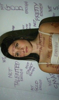 a woman with tattoos on her body laying on top of a bed covered in writing