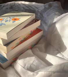 three books stacked on top of each other in front of a white bed sheet,