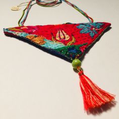 a colorful piece of cloth with tassels hanging from it's side on a white surface